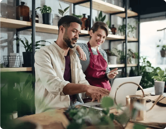 A young guy and girl behind the counter at a flower shop looking at a laptop