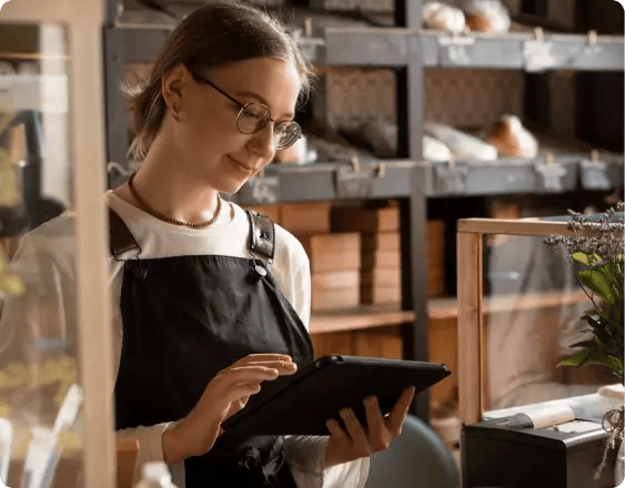 Young lady behind the counter of a bakery with an iPad